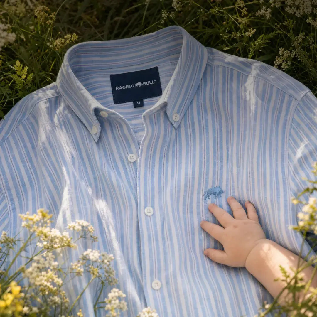 Father's Day Sorted Raging Bull Clothing - Baby's hand on a man's sky blue shirt, close-up.