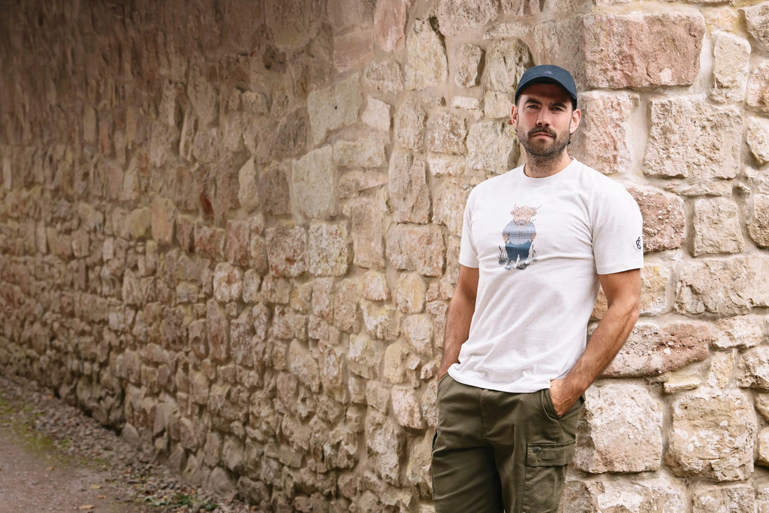 SUMMER LIVING, DONE IN STYLE Raging Bull Clothing, Man Leaning against a brick wall, waring Raging Bull Farmer Bully Boy t-shirt in white and Cargo short in olive.