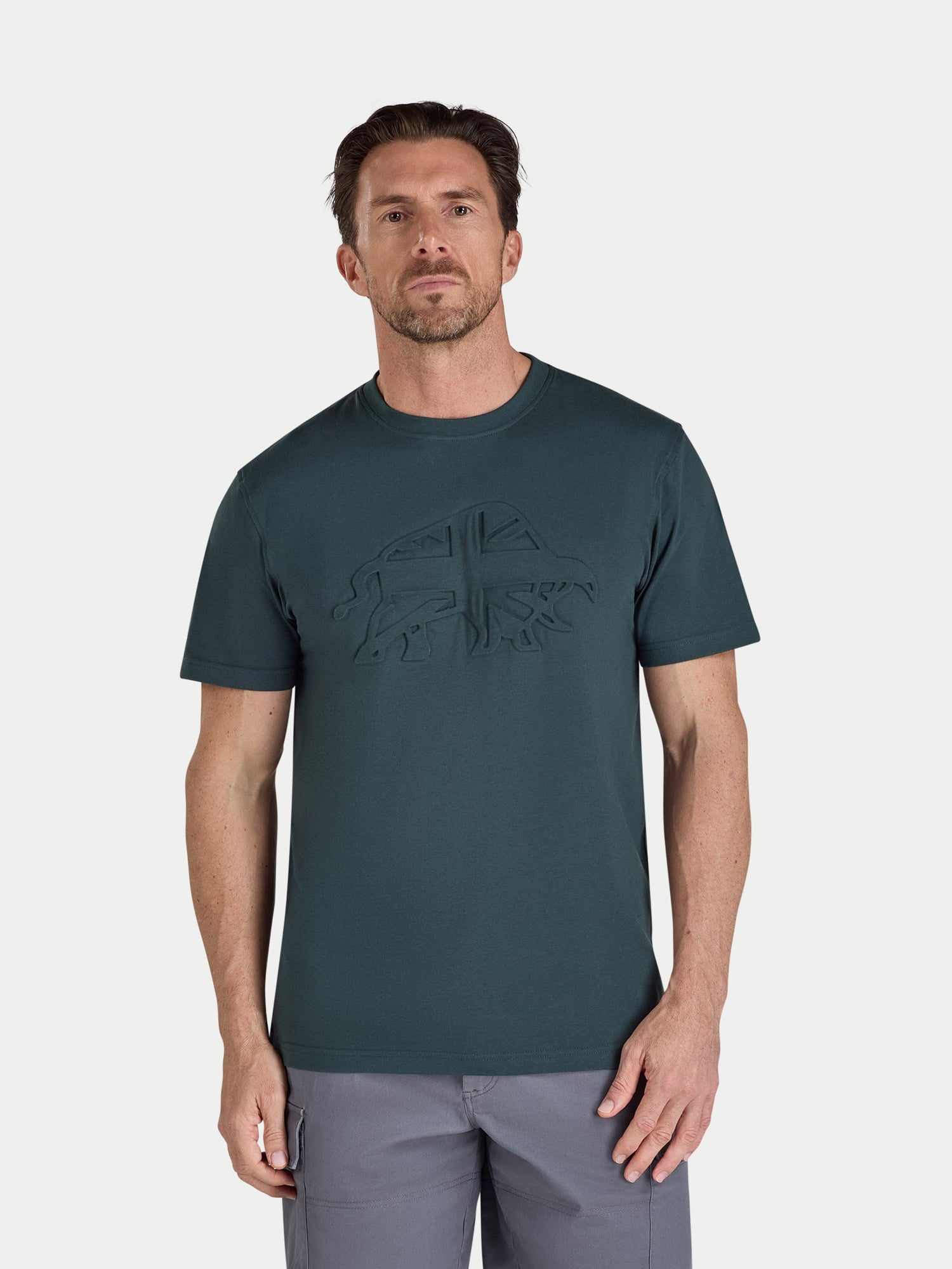 Man wearing a dark green t-shirt with a logo on a light gray background