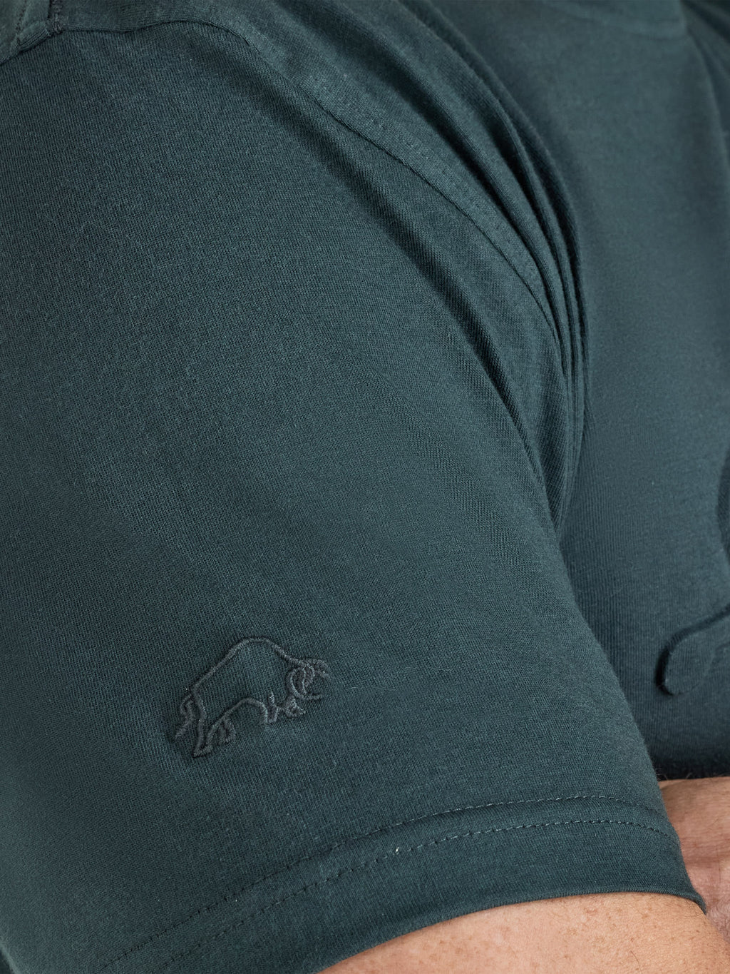 Close-up of a dark green t-shirt with a logo on the sleeve.