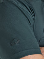 Close-up of a dark green t-shirt with a logo on the sleeve.