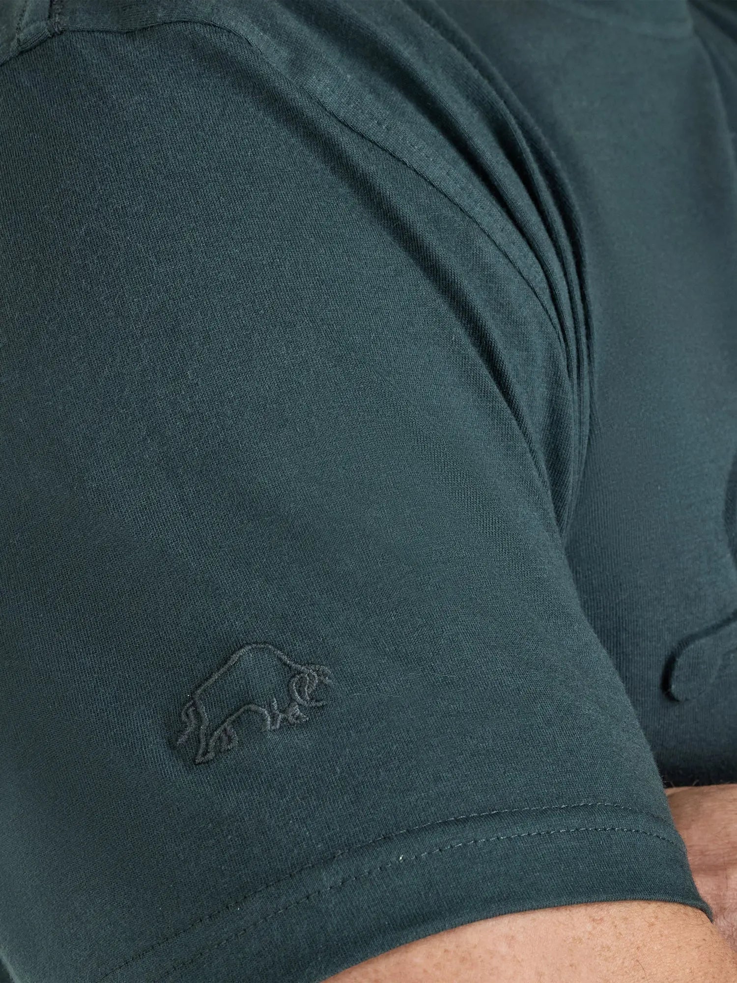 Close-up of a dark green t-shirt with a logo on the sleeve.