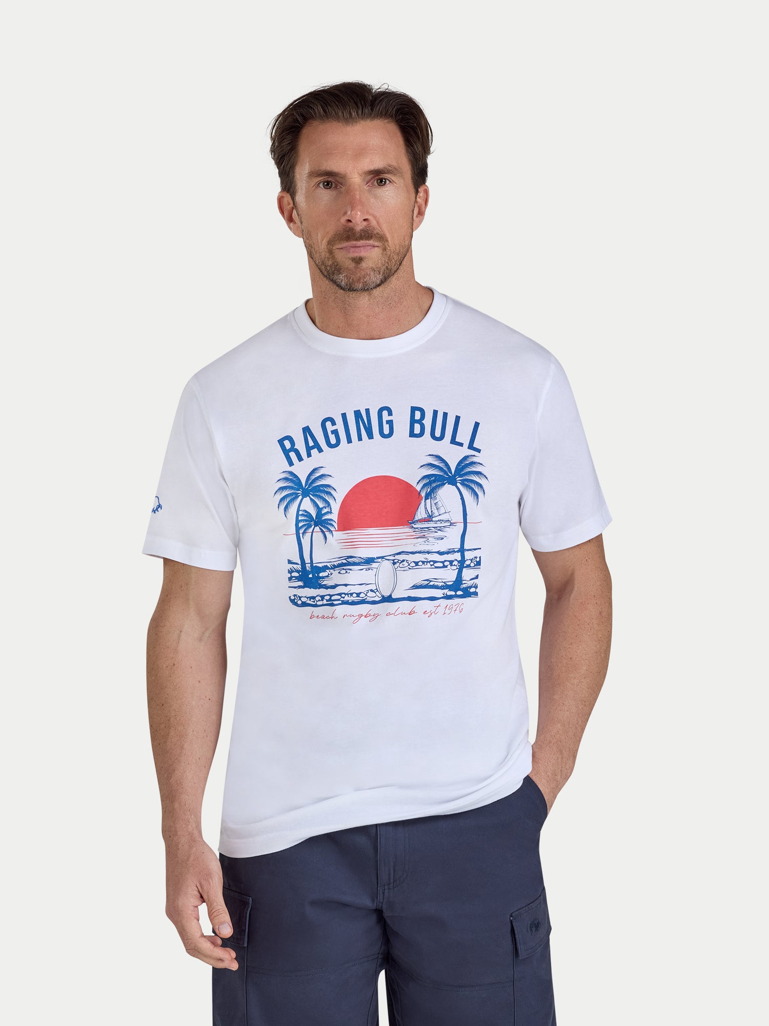 Man wearing a white t-shirt with 'Raging Bull' logo and design on a plain background