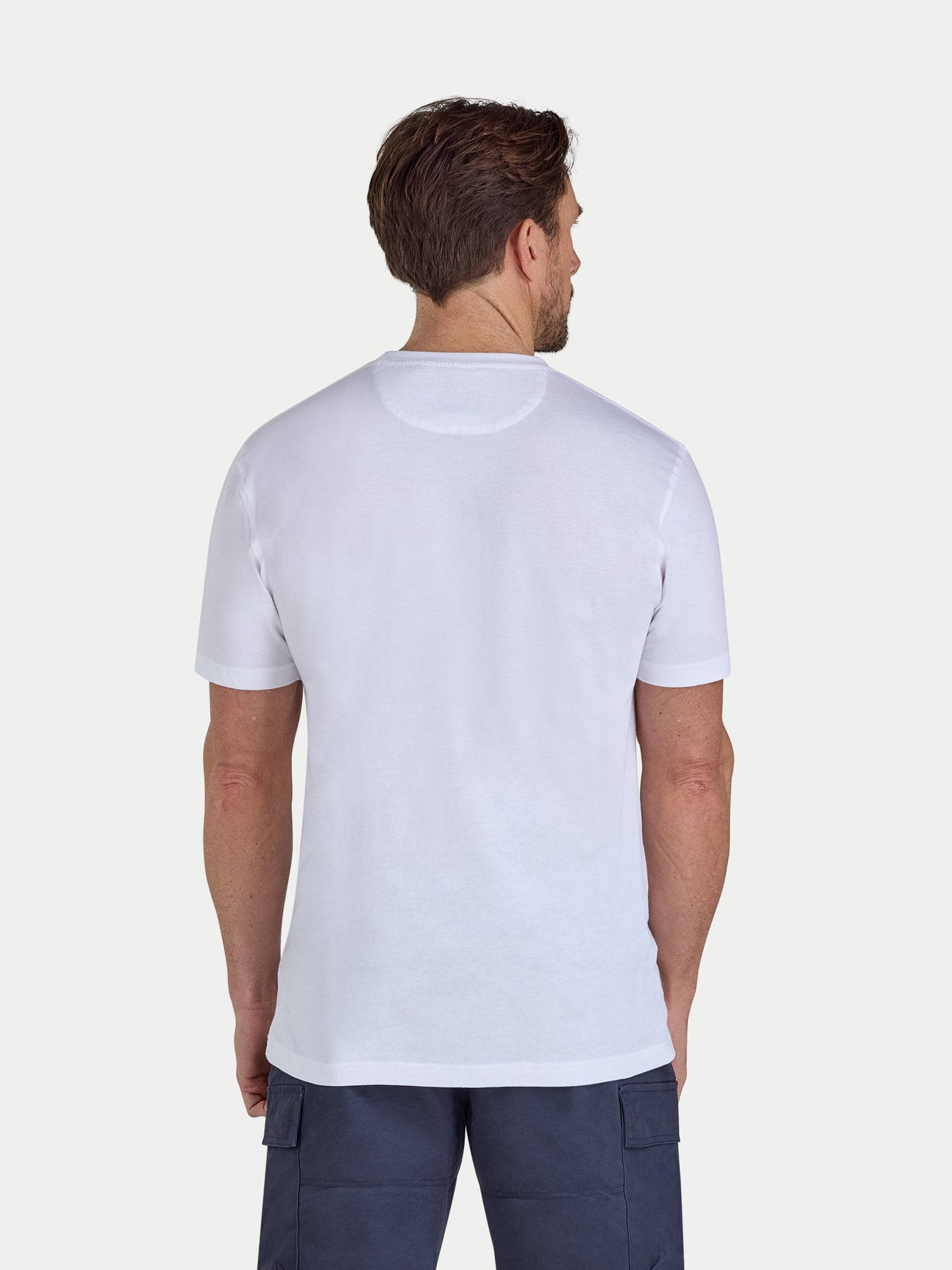 Man wearing a plain white t-shirt on a light gray background