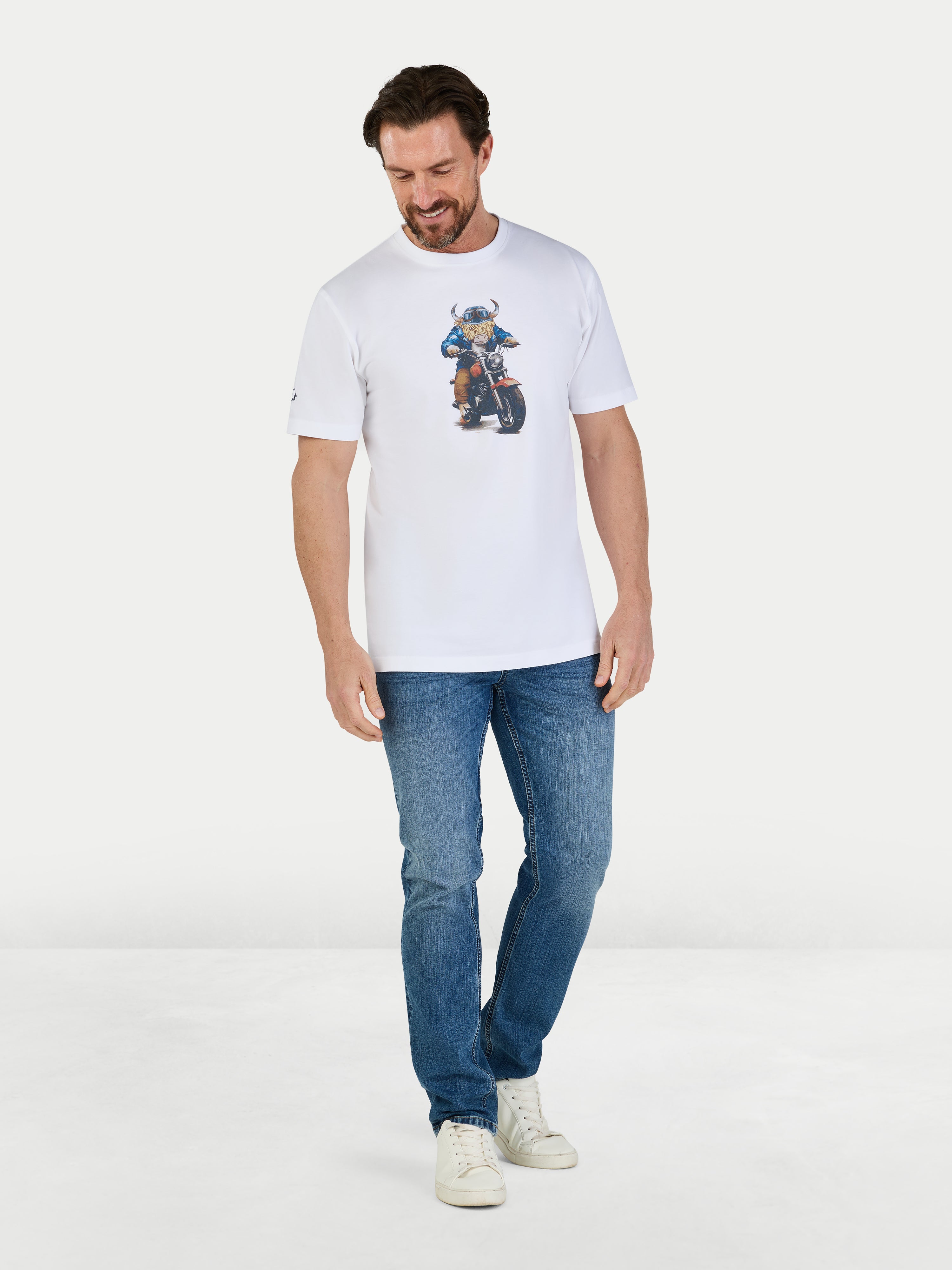 Man wearing a white t-shirt with a graphic design and blue jeans on a light gray background