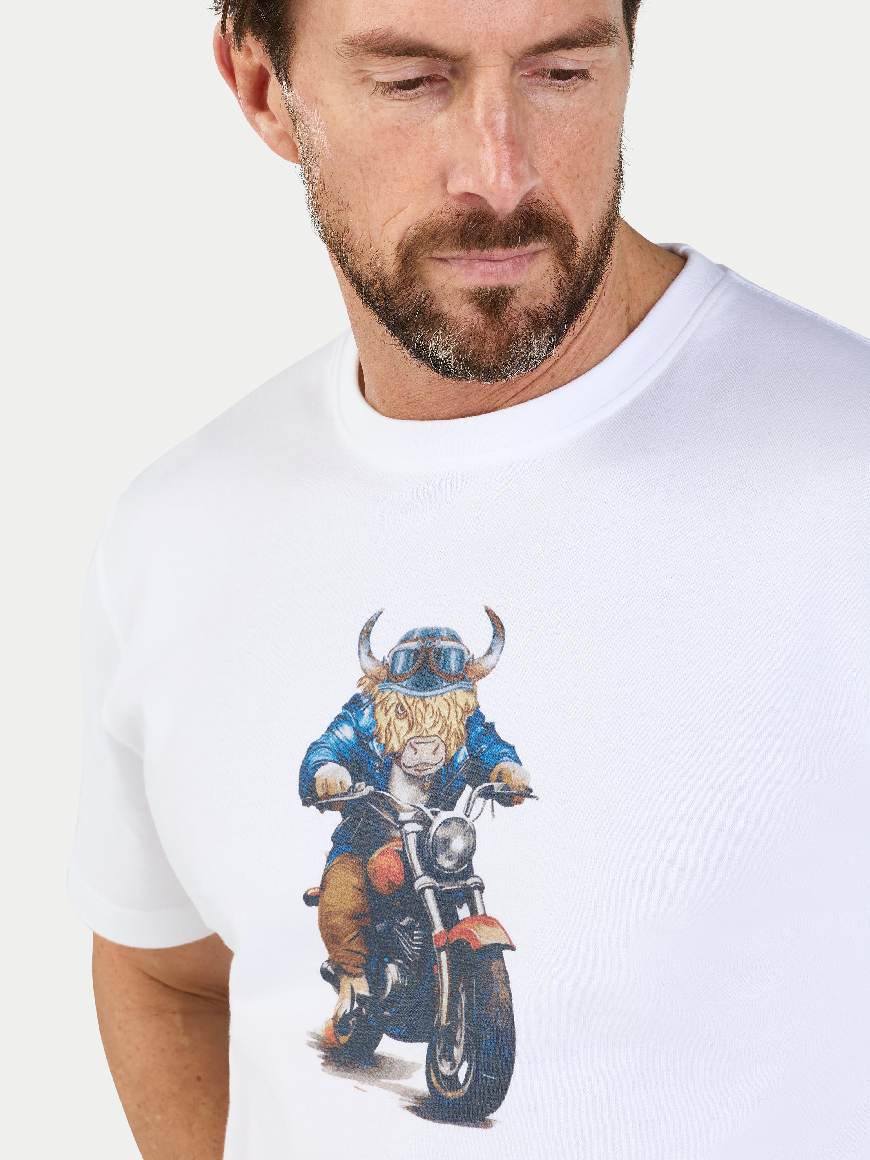 Man wearing a white t-shirt with a graphic of a cow on a motorcycle.