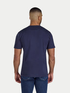 Man wearing a navy blue t-shirt and jeans on a white background