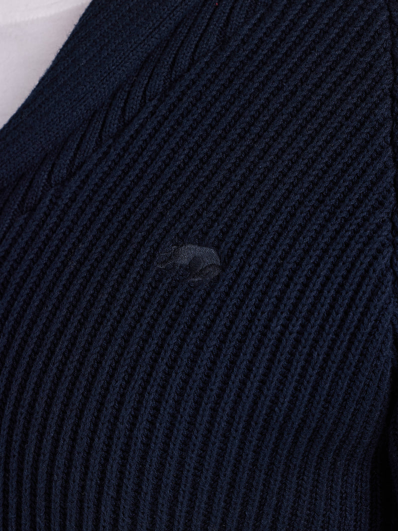 Close-up of a dark blue ribbed sweater with a brand logo.