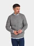 Man wearing a gray cable knit sweater on a light gray background