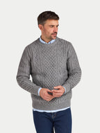 Man wearing a gray cable knit sweater on a light gray background