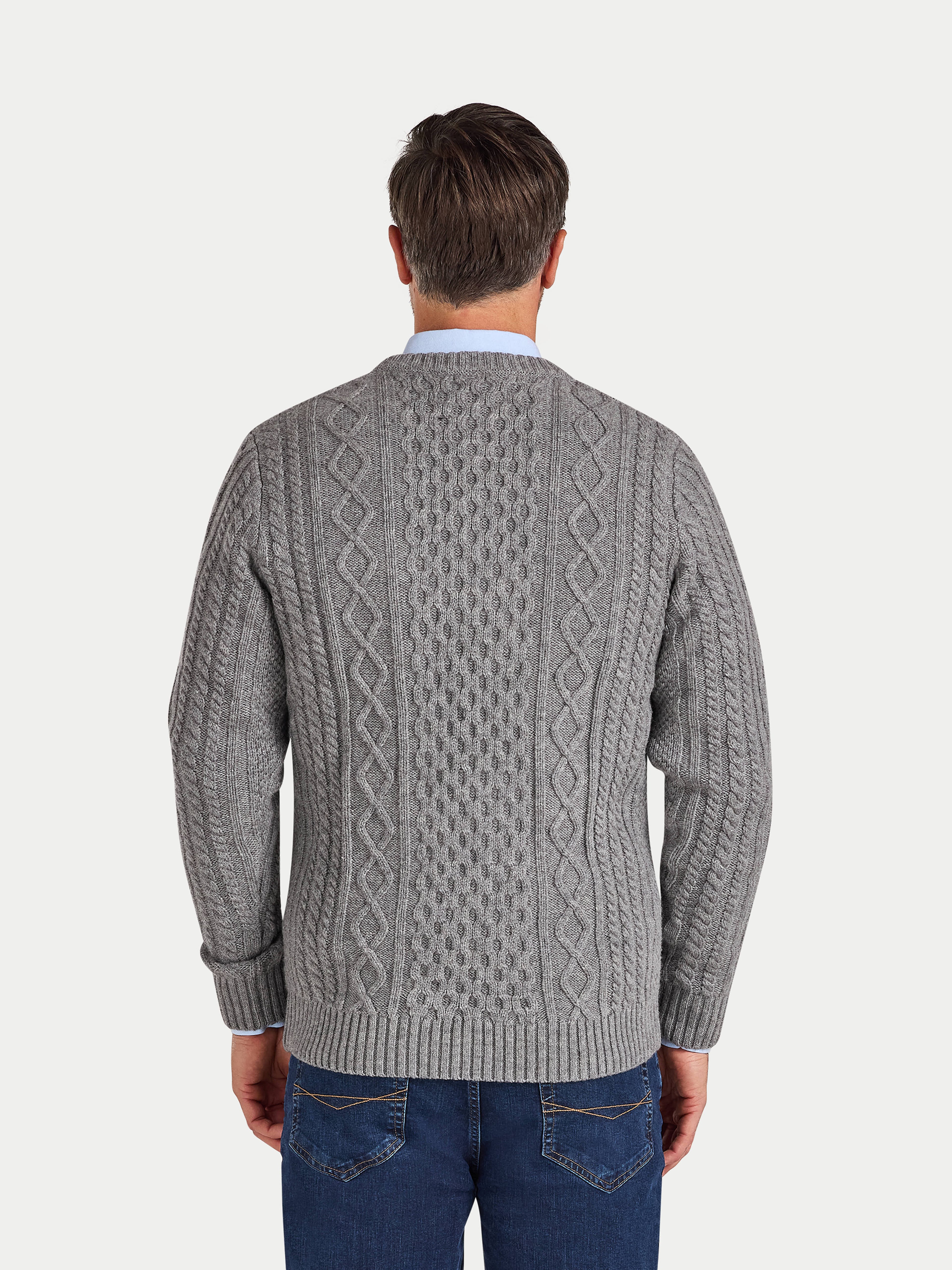 Man wearing a gray cable knit sweater on a white background