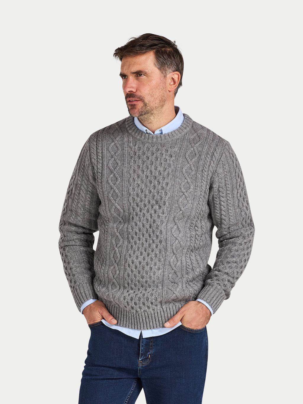 Man wearing a gray cable knit sweater on a light gray background