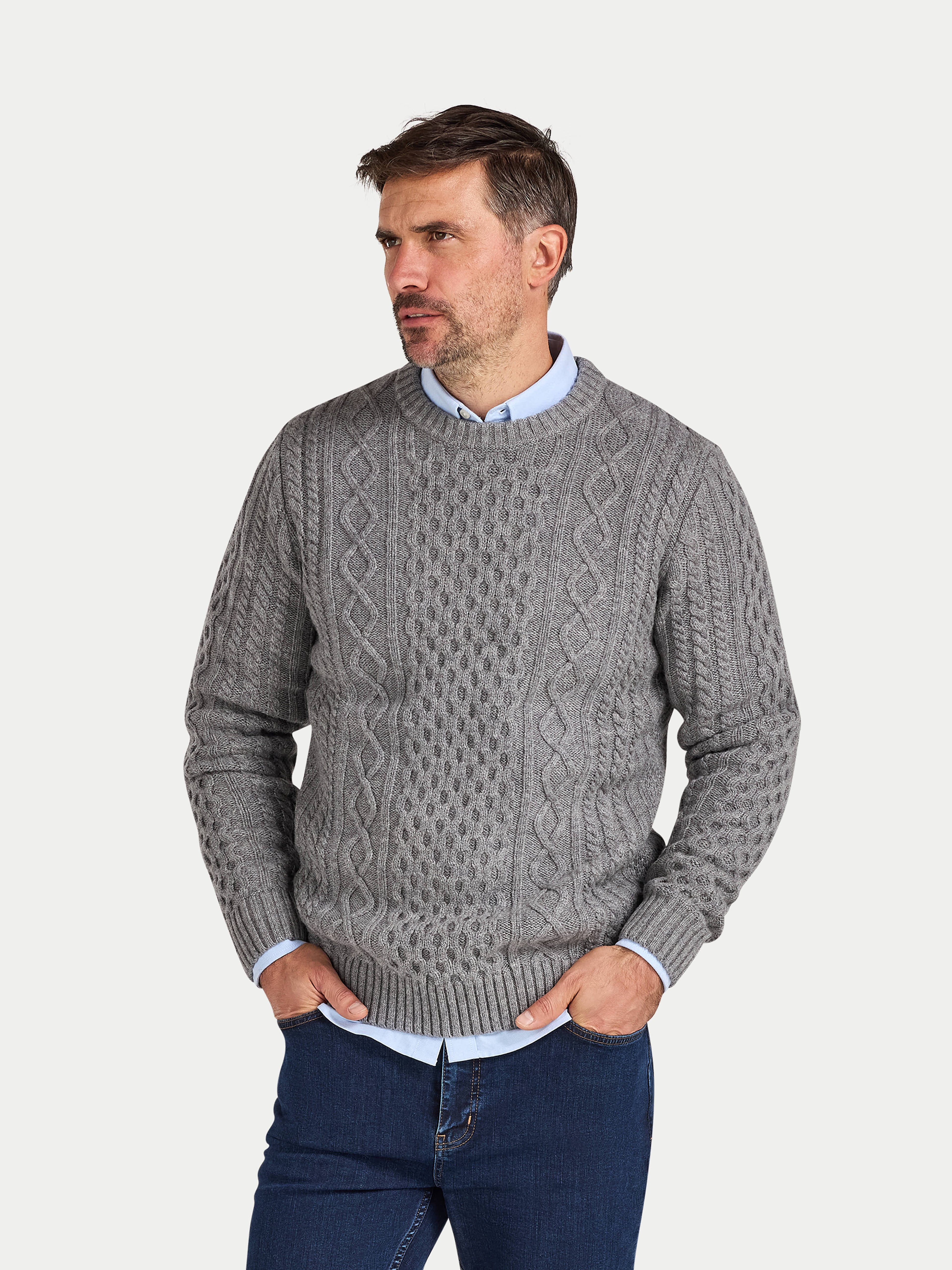 Man wearing a gray cable knit sweater on a light gray background