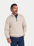 Man wearing a beige cable knit sweater with a quarter zip on a white background