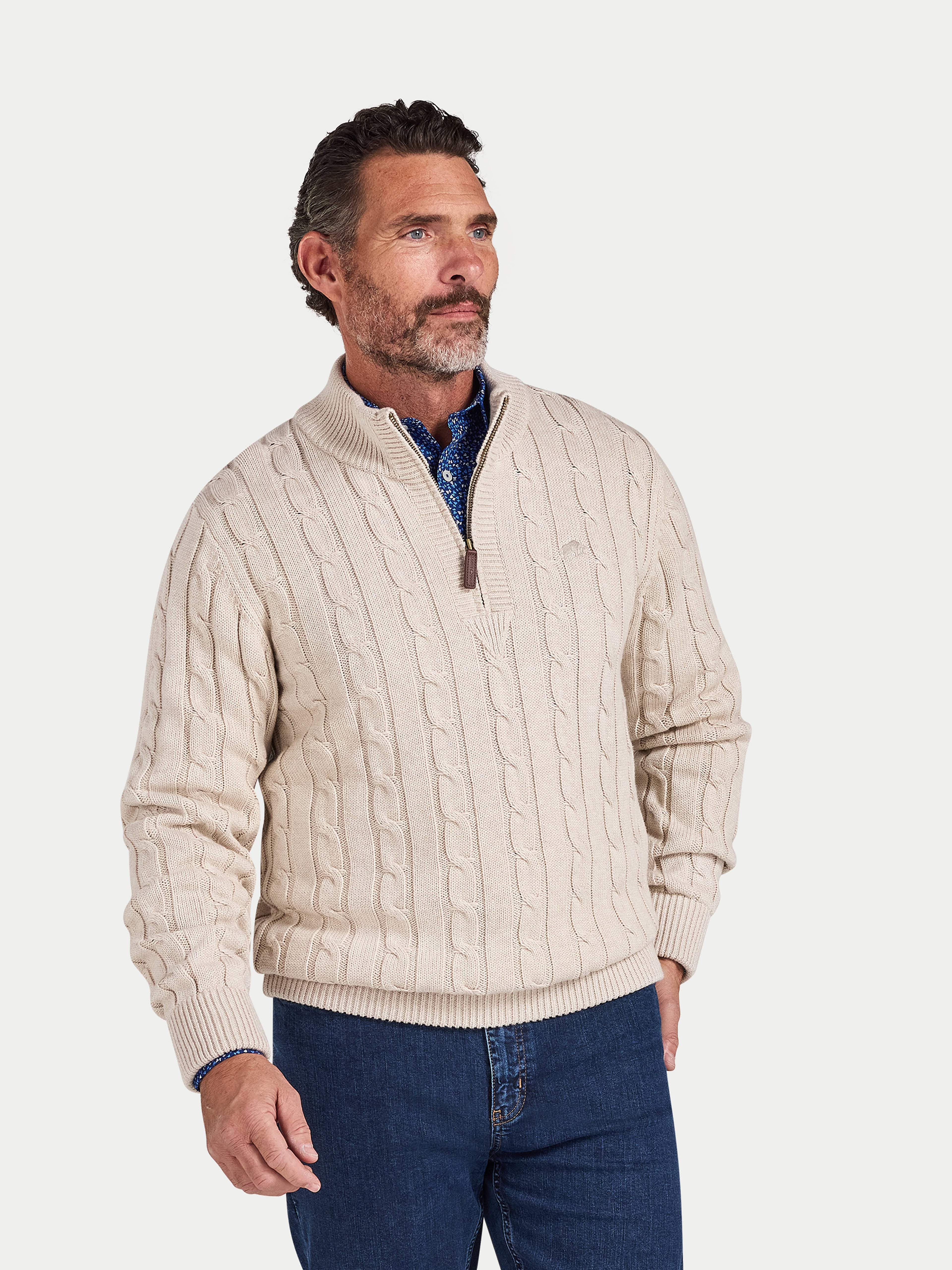 Man wearing a beige cable knit sweater with a quarter zip on a white background