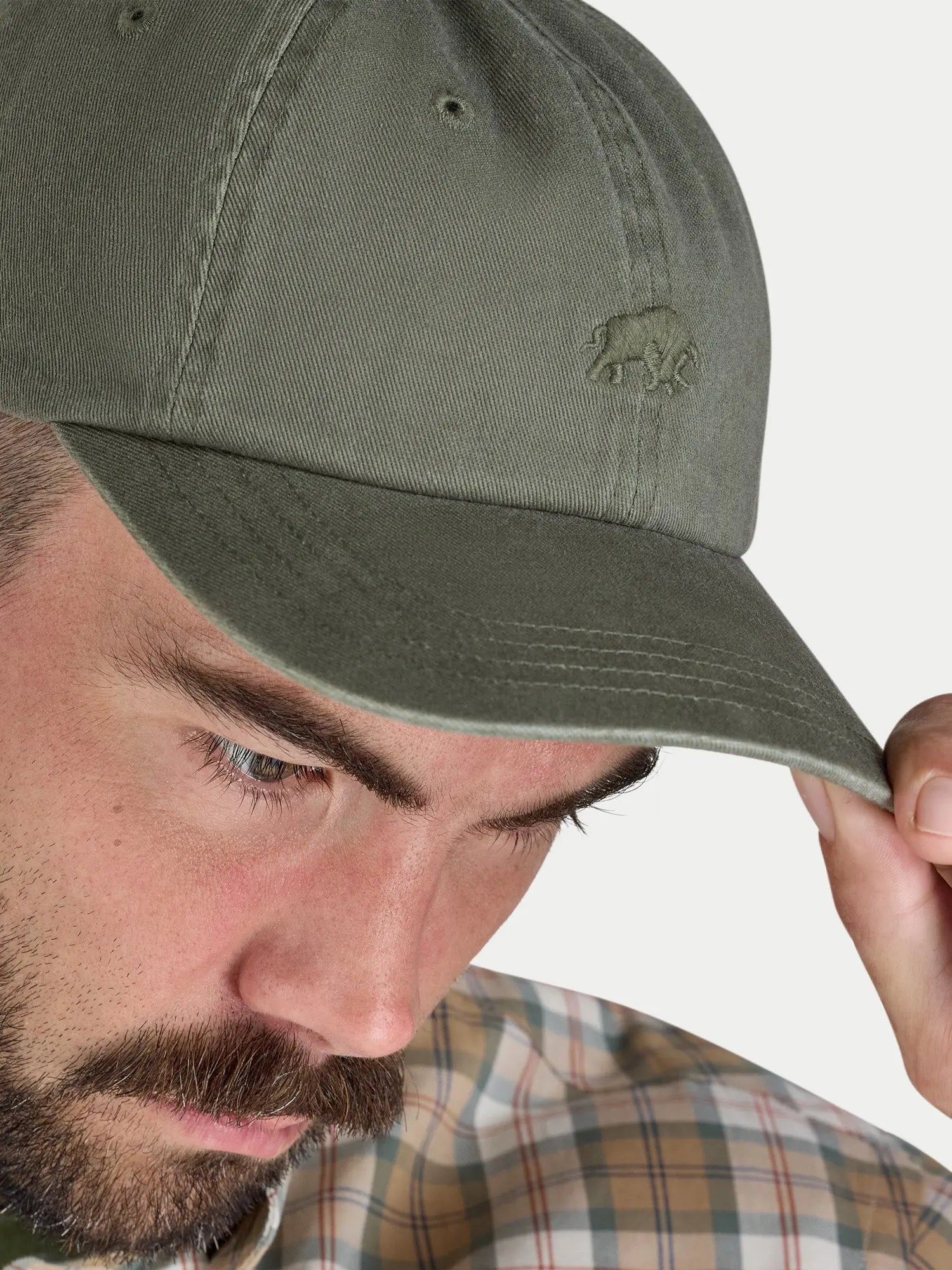 Man wearing a green cap with a logo on a white background