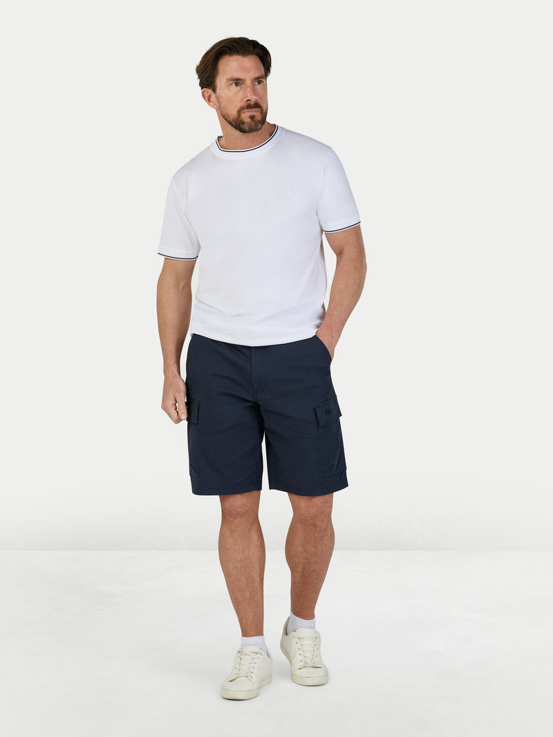 Man wearing a white t-shirt and navy cargo shorts on a white background