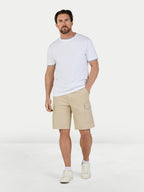 Man wearing a white t-shirt and beige shorts on a light gray background