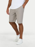 Person wearing beige shorts and white shoes on a white background