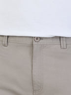 Close-up of beige pants with a white shirt underneath on a light gray background