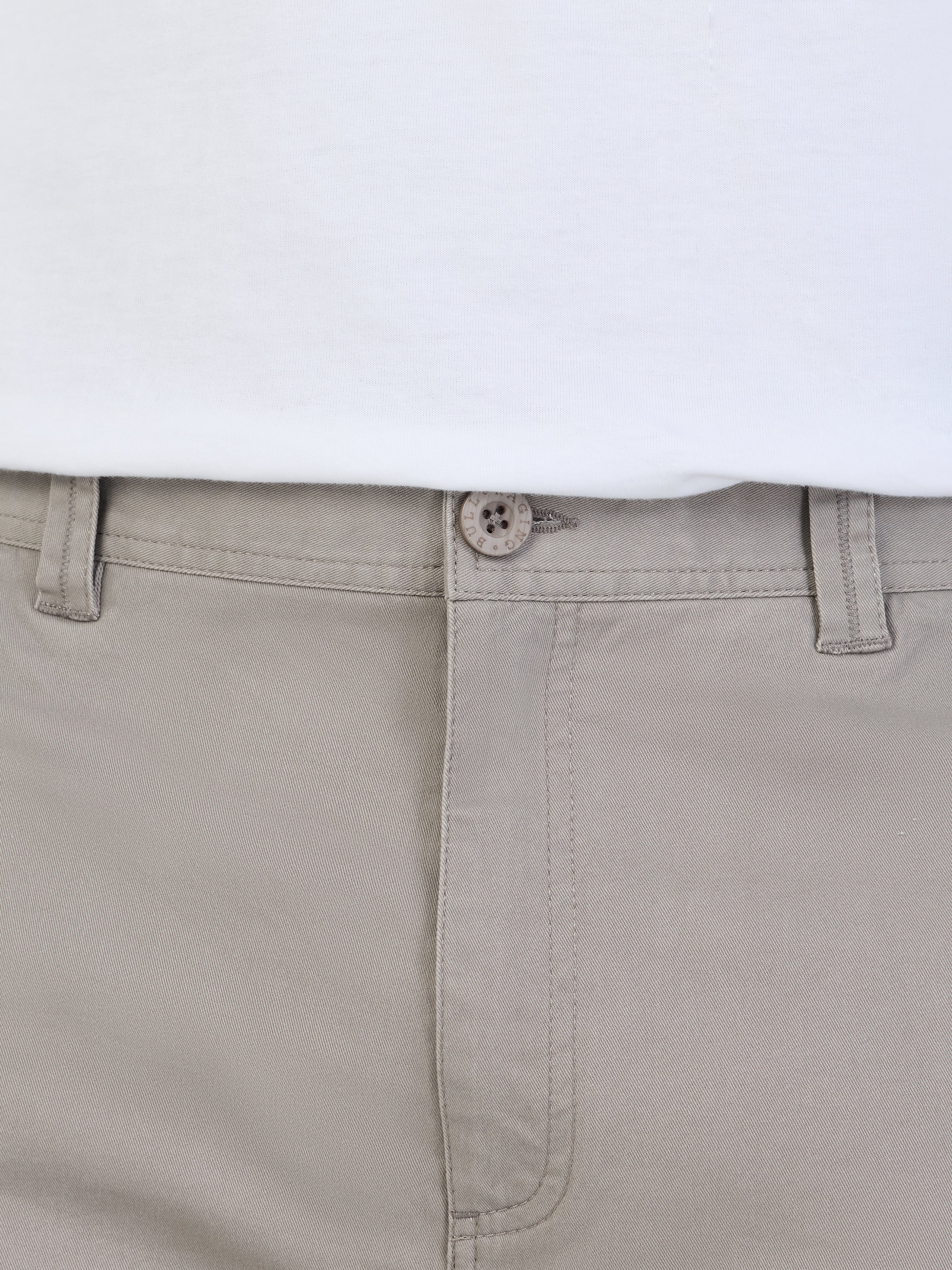 Close-up of beige pants with a white shirt underneath on a light gray background