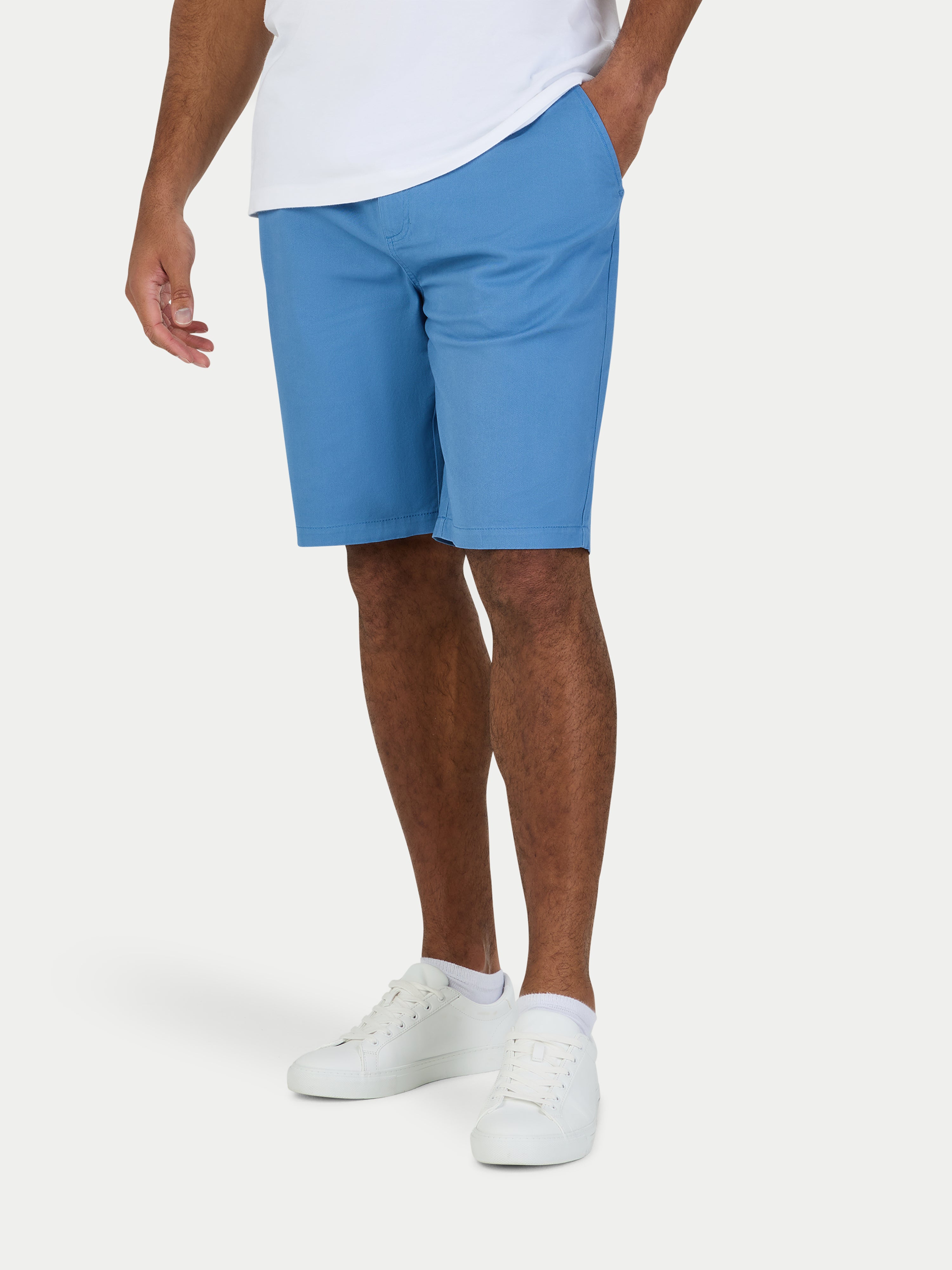 Person wearing blue shorts and white shoes on a white background