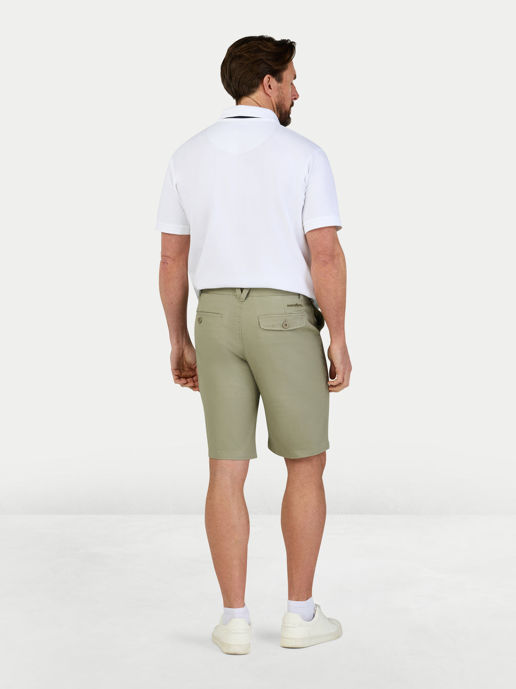 Man wearing a white polo shirt and green shorts on a white background