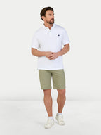 Man wearing classic chino shorts in sage and a white polo top on a white backround.