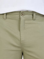 Close-up of sage green shorts with a button on a white background