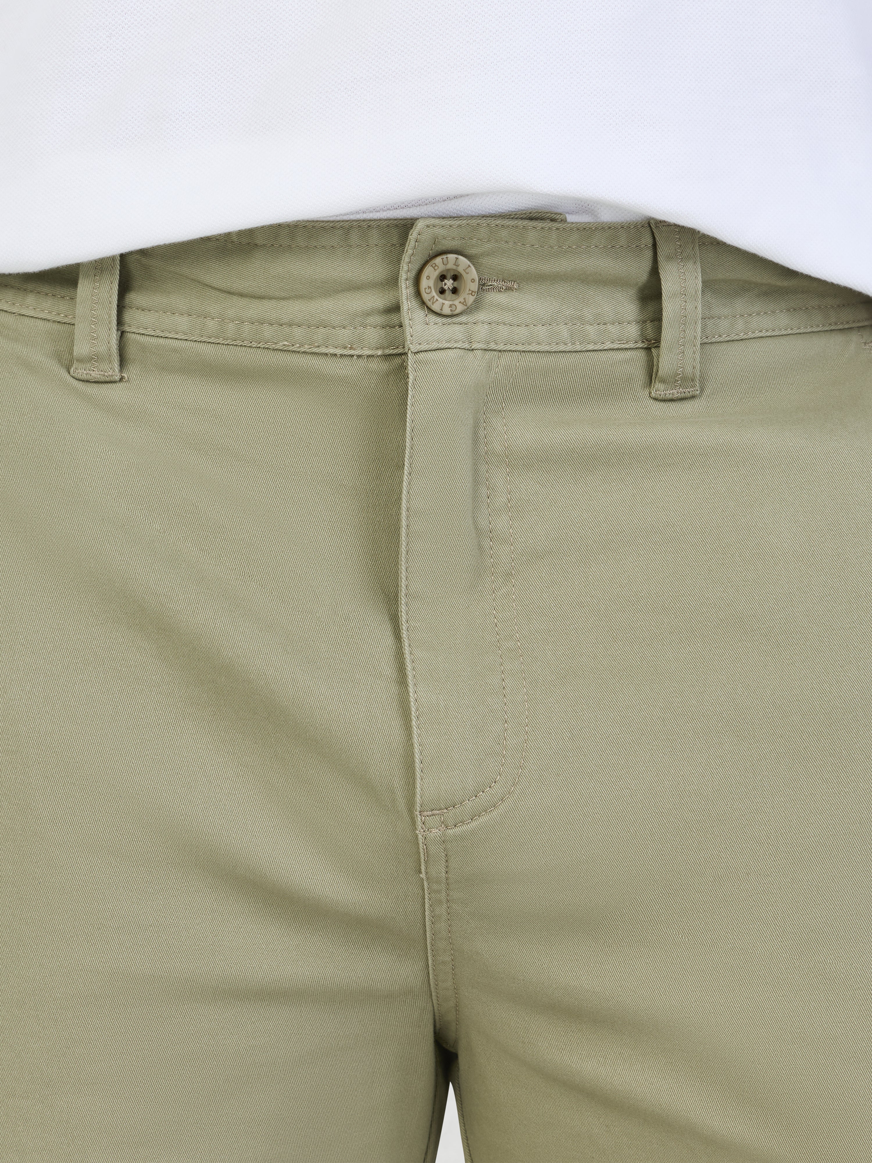 Close-up of sage green shorts with a button on a white background