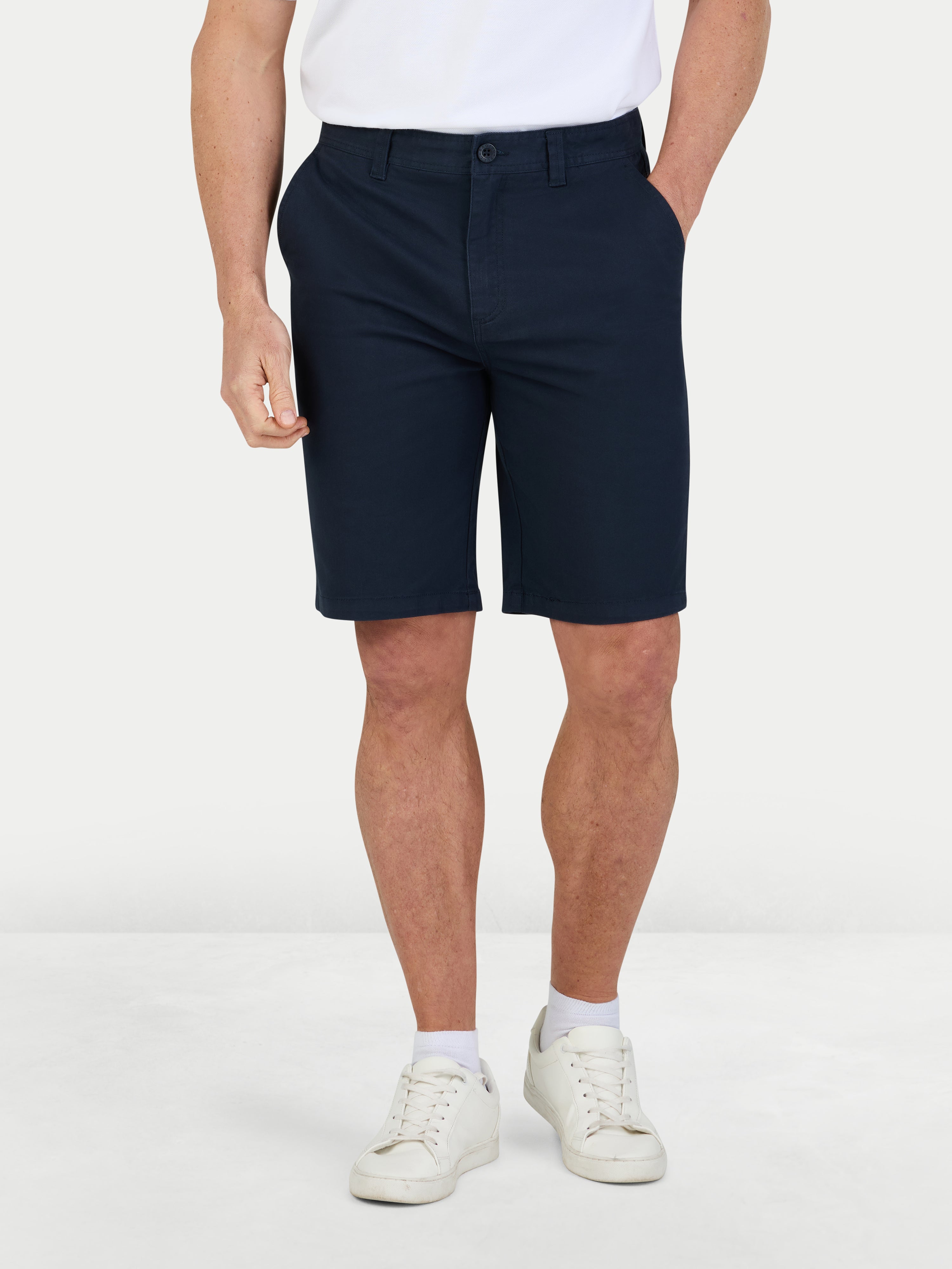 Person wearing navy shorts and white sneakers on a white background