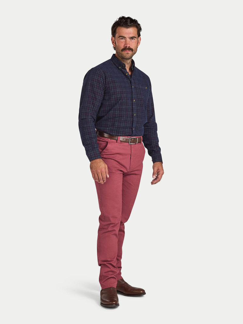Man wearing a blue checkered shirt and red pants on a white background
