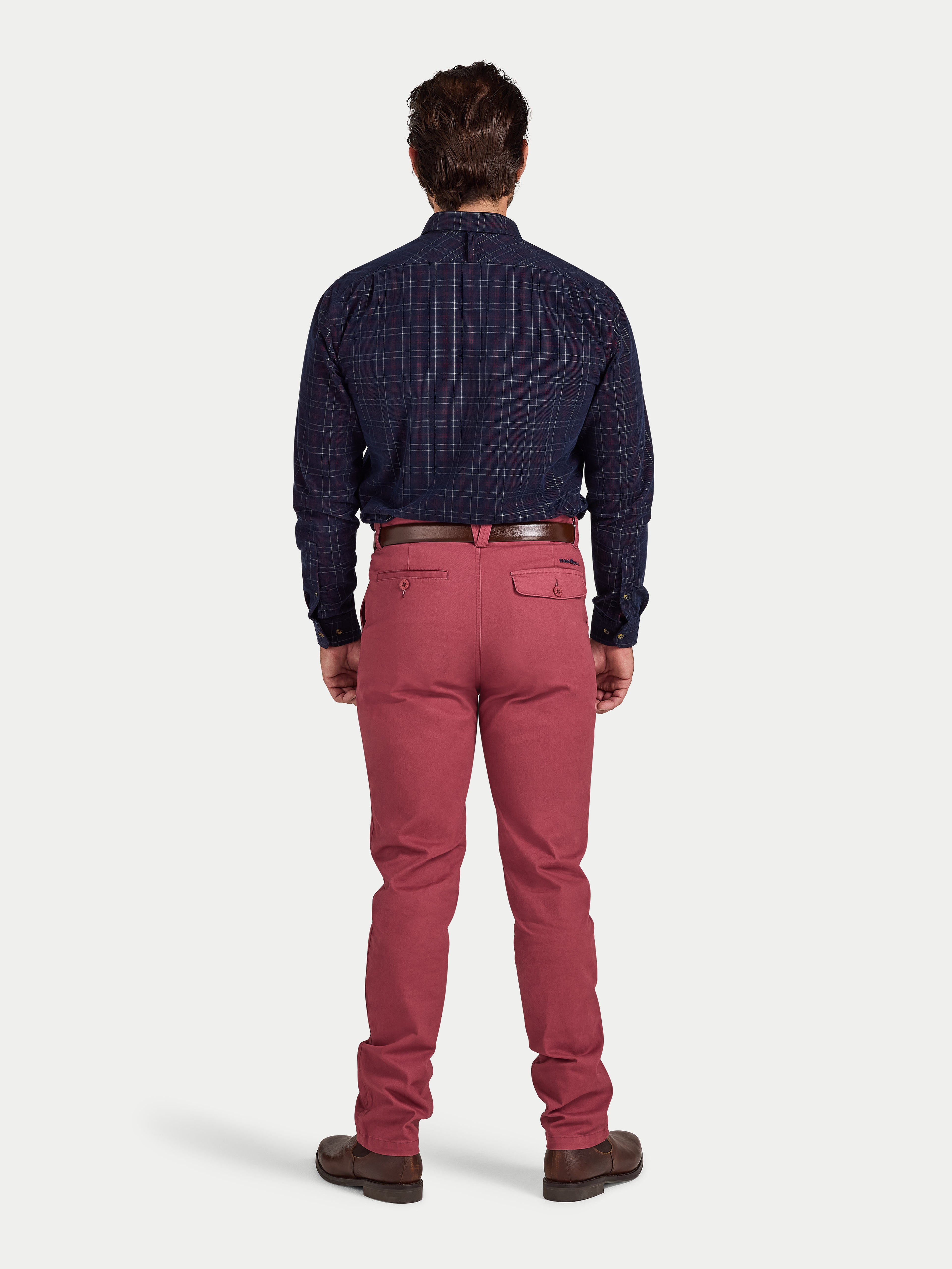 Man wearing a dark plaid shirt and red pants on a white background