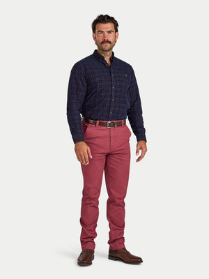 Man wearing a navy checkered shirt and red pants on a white background