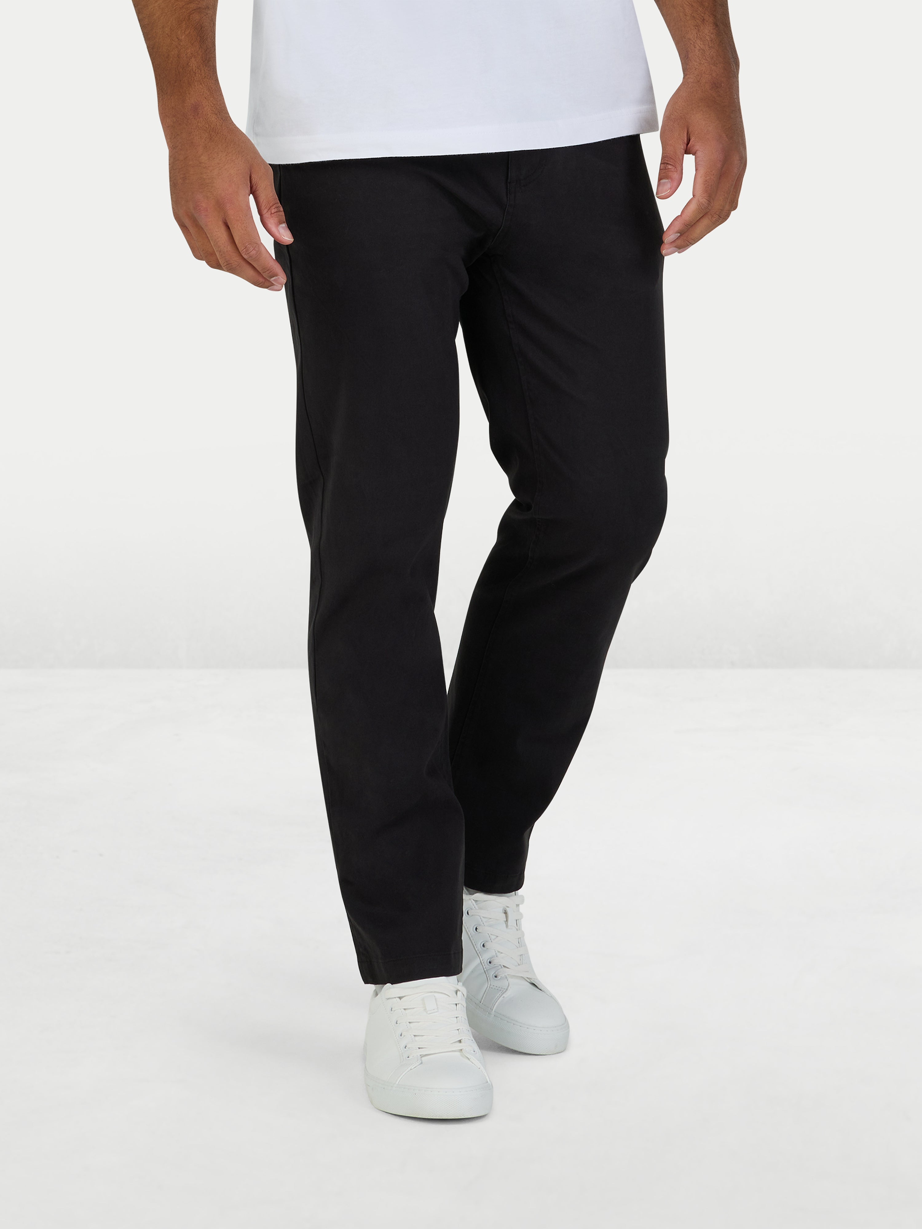 Person wearing black pants and white shoes on a white background