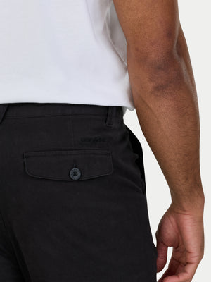 Person wearing black pants with a pocket detail on a white background