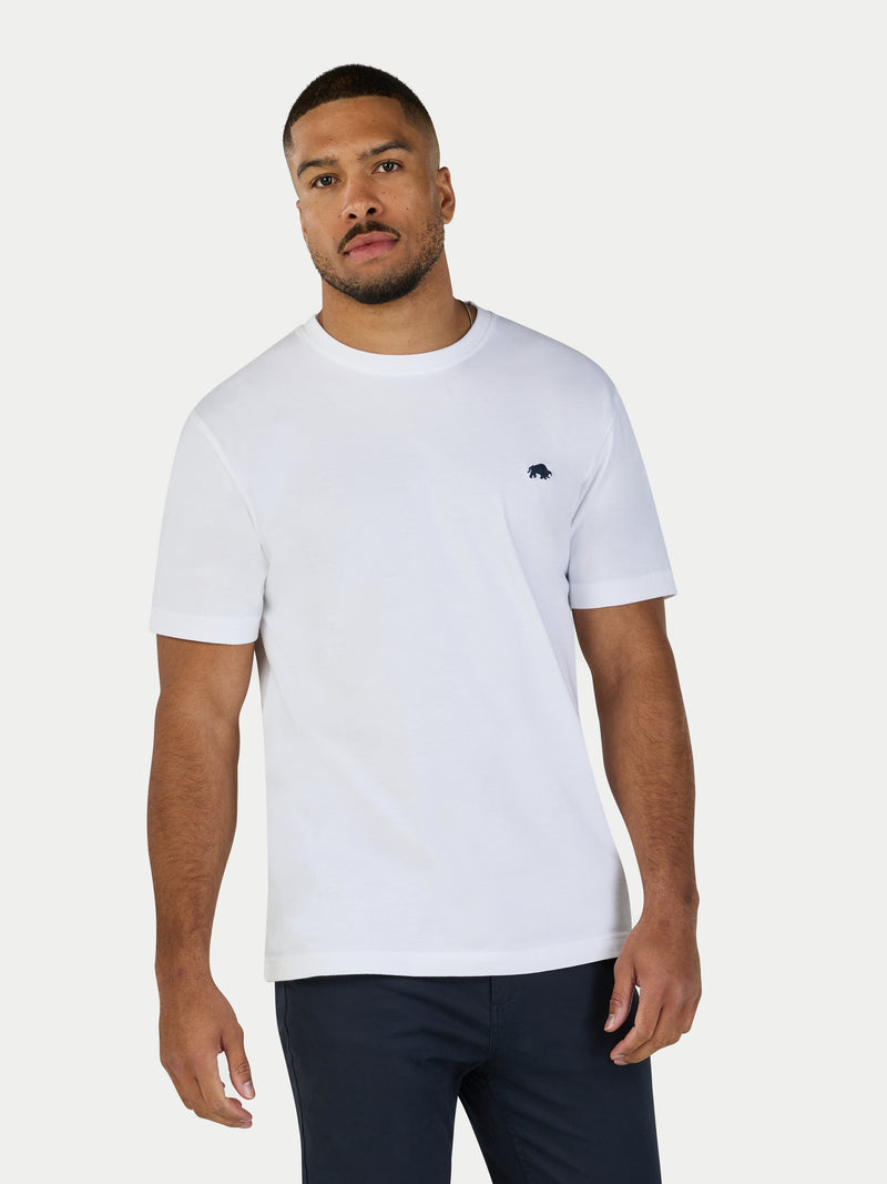 Man wearing a white t-shirt with a small logo on a white background