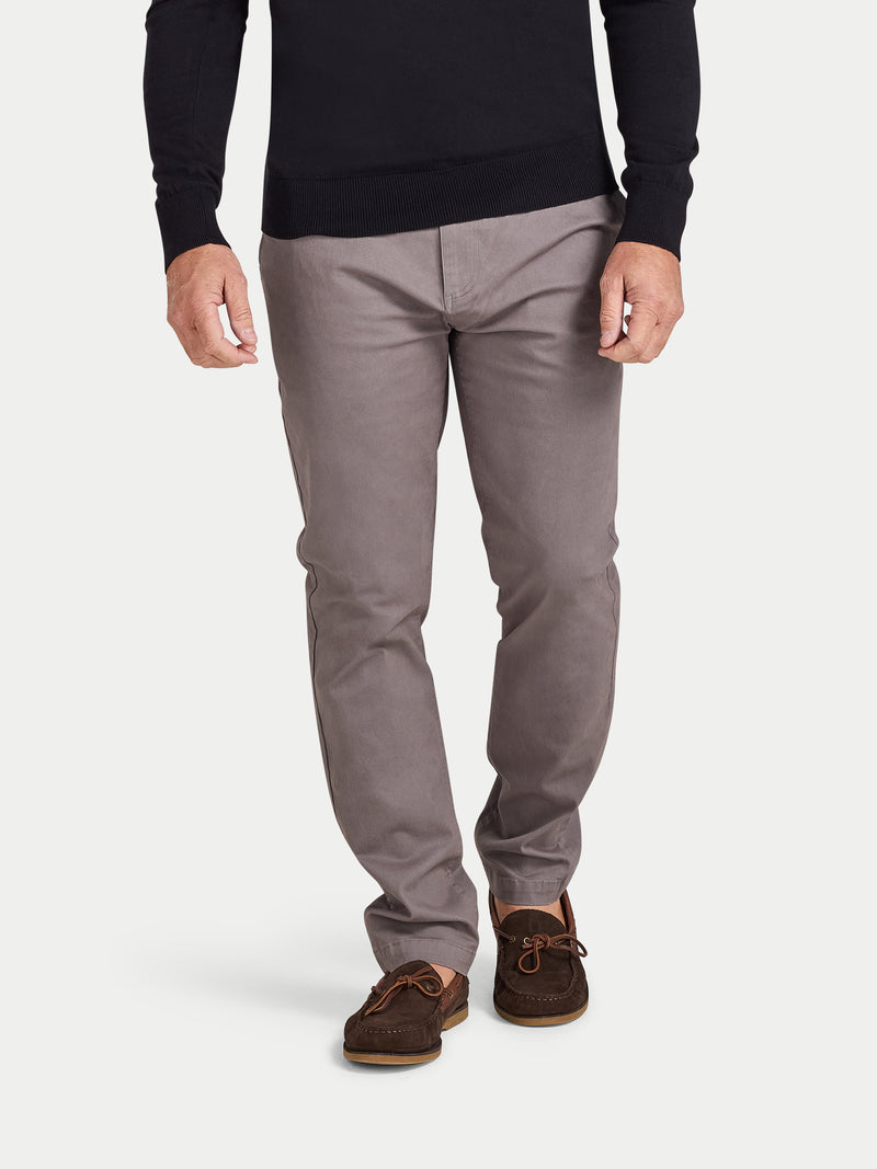 Person wearing gray pants and brown shoes on a white background