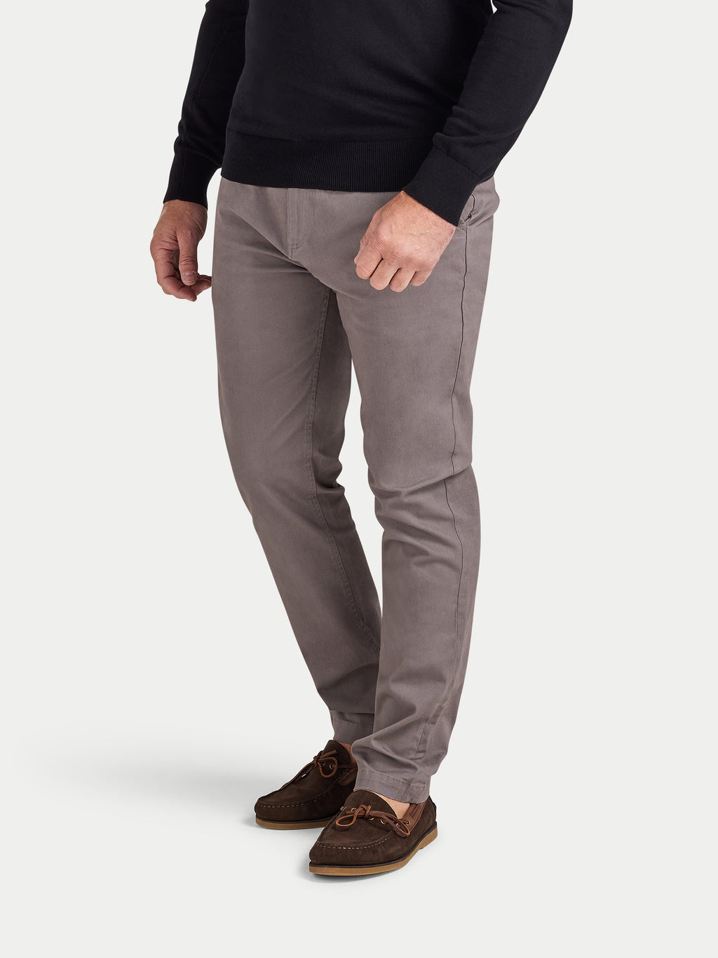 Person wearing gray pants and a black sweater on a white background