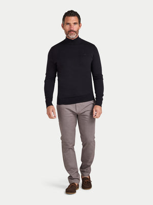 Man wearing a black sweater and gray pants on a white background