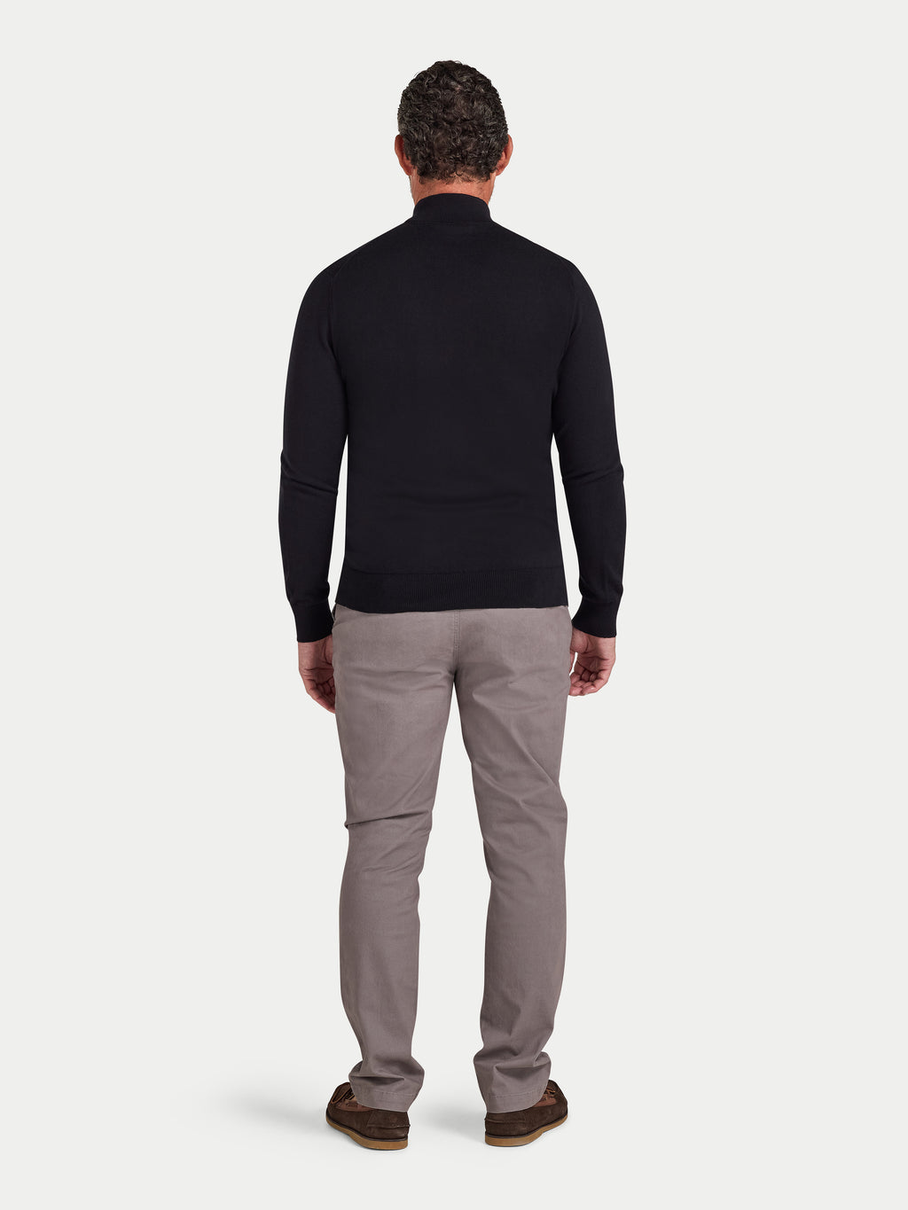 Man wearing a black long-sleeve shirt and gray pants on a white background