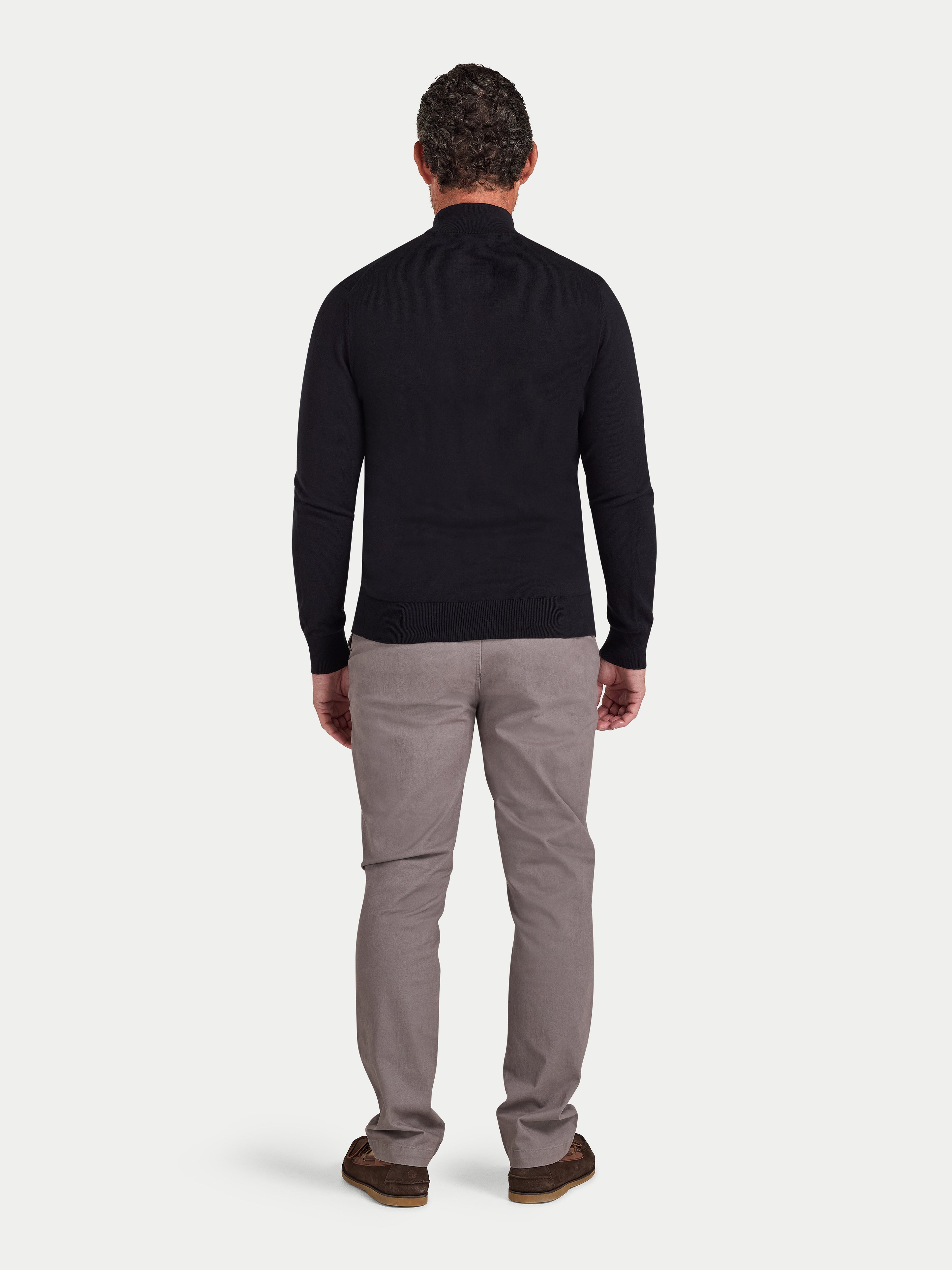 Man wearing a black long-sleeve shirt and gray pants on a white background