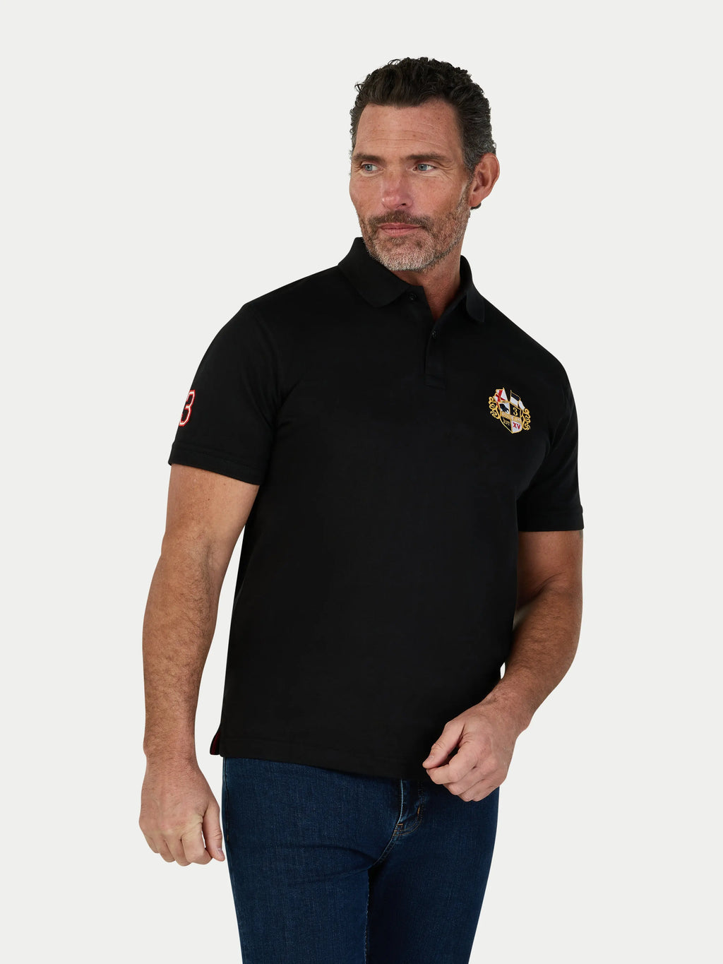 Man wearing a black polo shirt with a logo on a white background