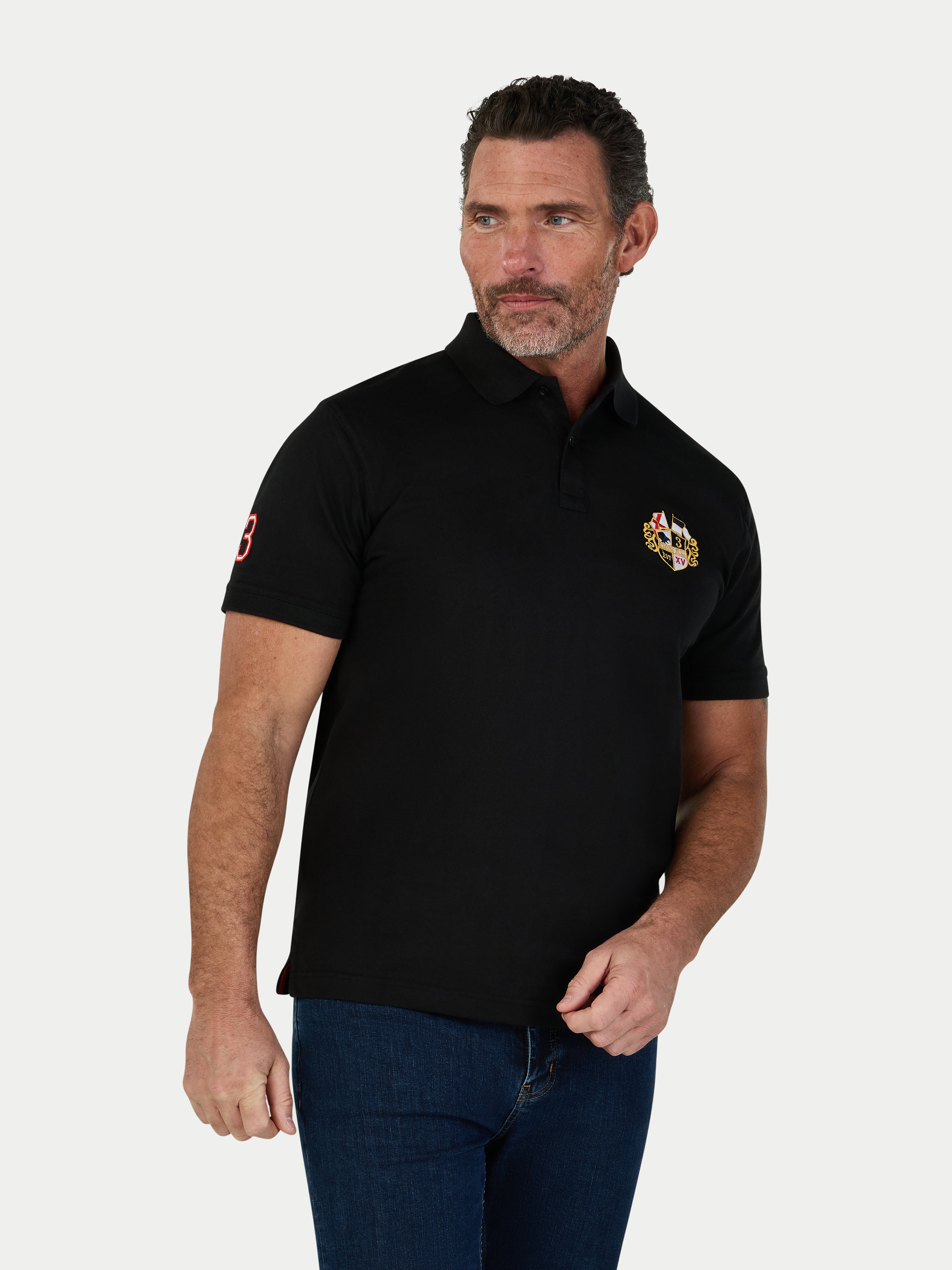 Man wearing a black polo shirt with a logo on a white background