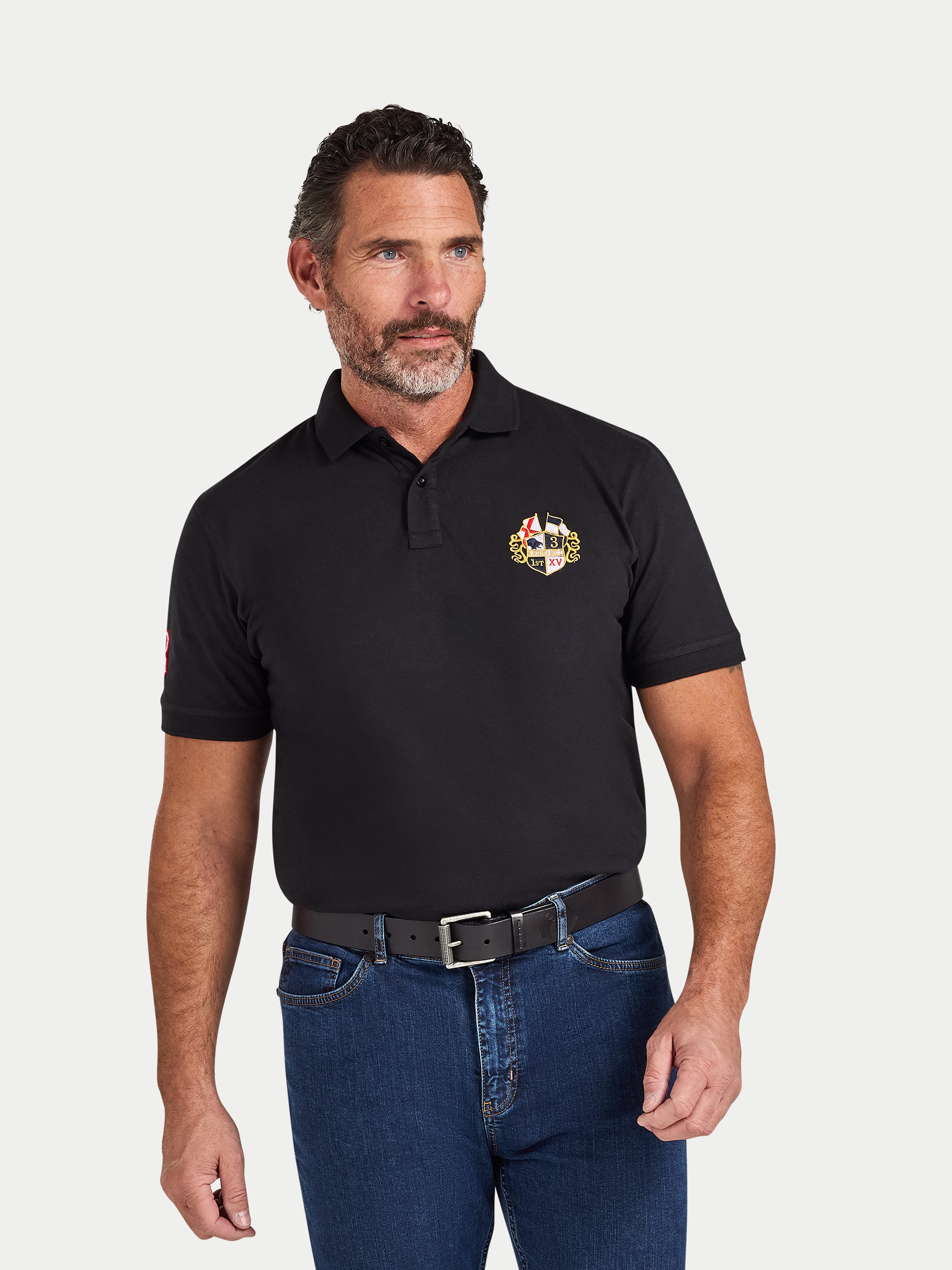 Man wearing a black polo shirt with a logo on a white background