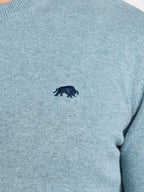 Close-up of a light blue sweater with a dark blue logo on a white background