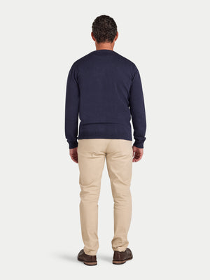 Man wearing a navy sweater and beige pants on a white background