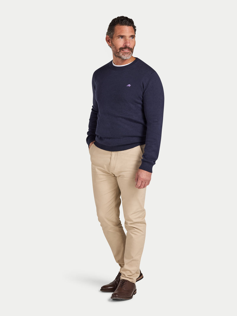 Man wearing a navy sweater and beige pants on a white background