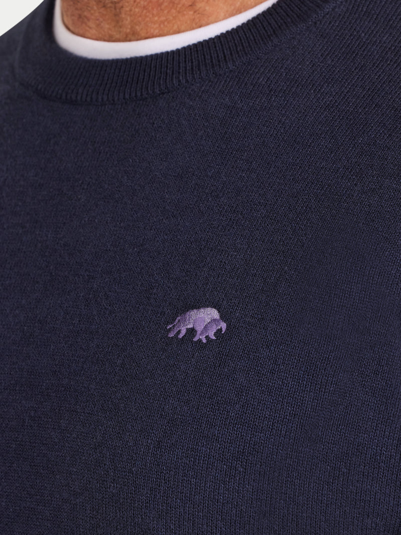 Navy sweater with a small purple logo on a plain background