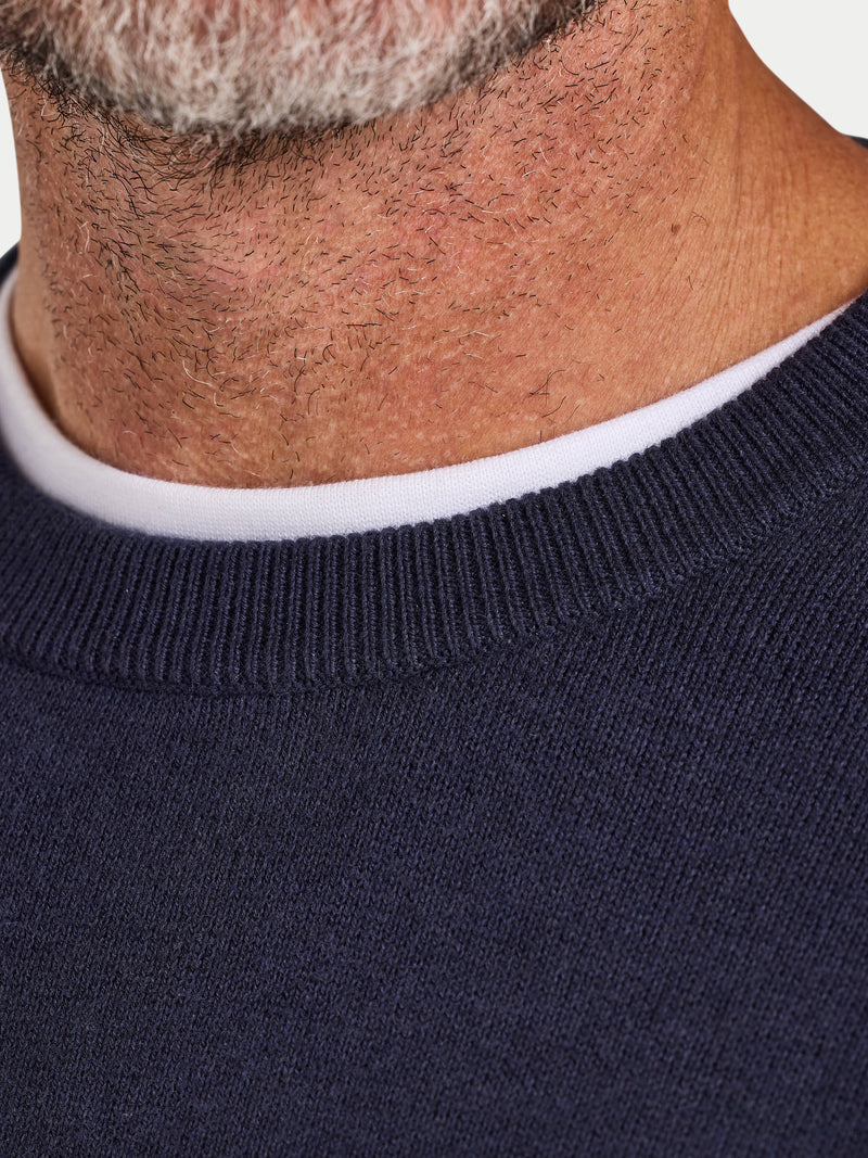 Close-up of a person wearing a navy sweater with a white collar.